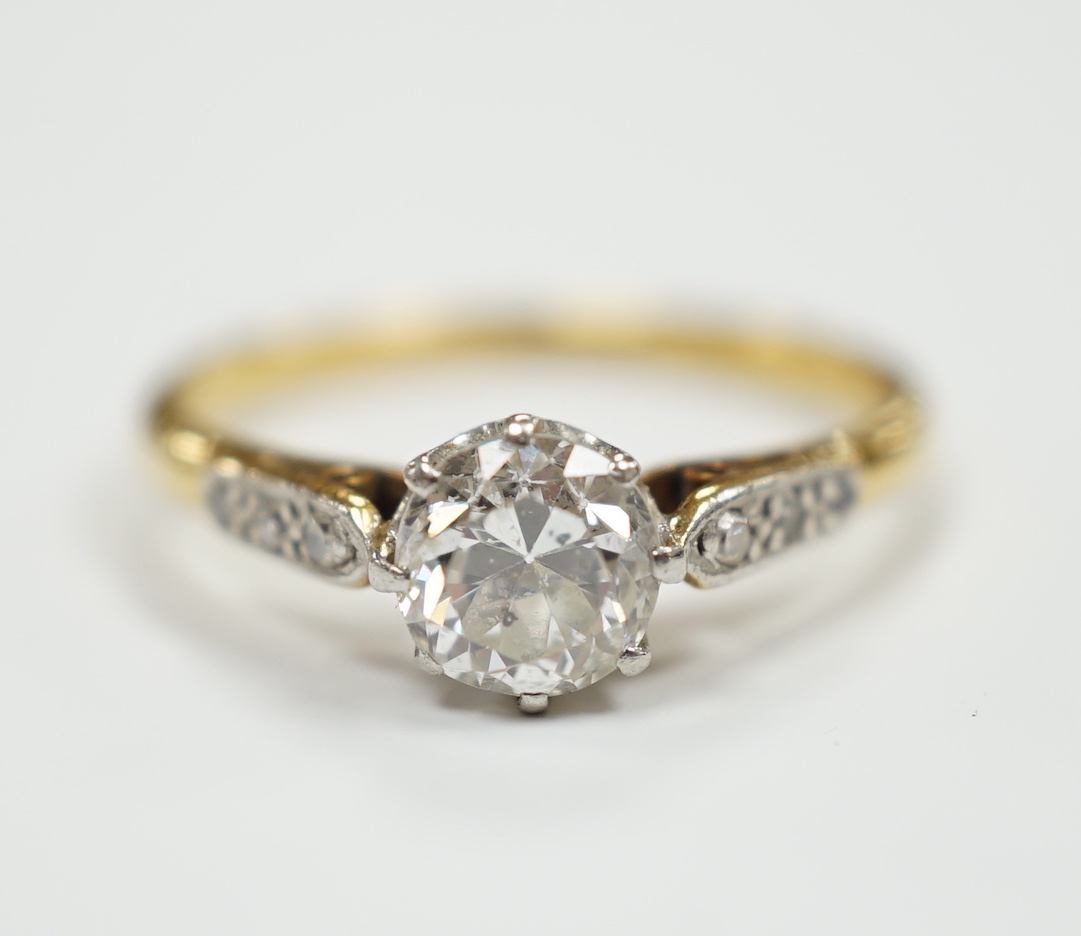 An 18ct, plat. and single stone diamond ring, with diamond set shoulders, the central stone measuring 6mm in diameter.